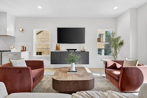 A modern living room with a flat-screen TV, two sofas, a coffee table, and a bookshelf. - Rooftop with Dining, Walk to Restaurants and Brewery (Nashville)
