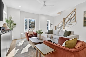A modern living room with a sofa, armchair, coffee table, and a staircase. - Rooftop with Dining, Walk to Restaurants and Brewery (Nashville)