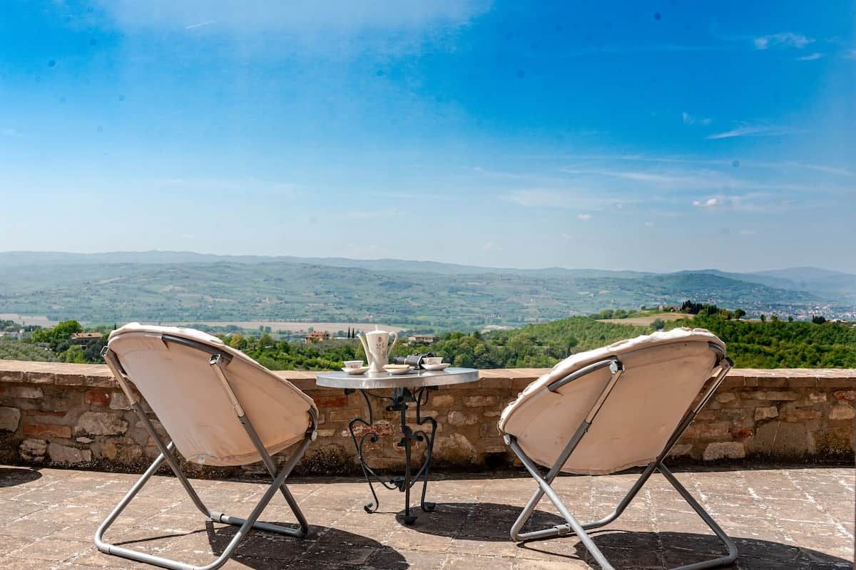Eine Terrasse mit zwei Stühlen und einem Tisch mit Blick auf eine Berglandschaft.