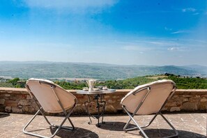 Eine Terrasse mit zwei Stühlen und einem Tisch mit Blick auf eine Berglandschaft.
