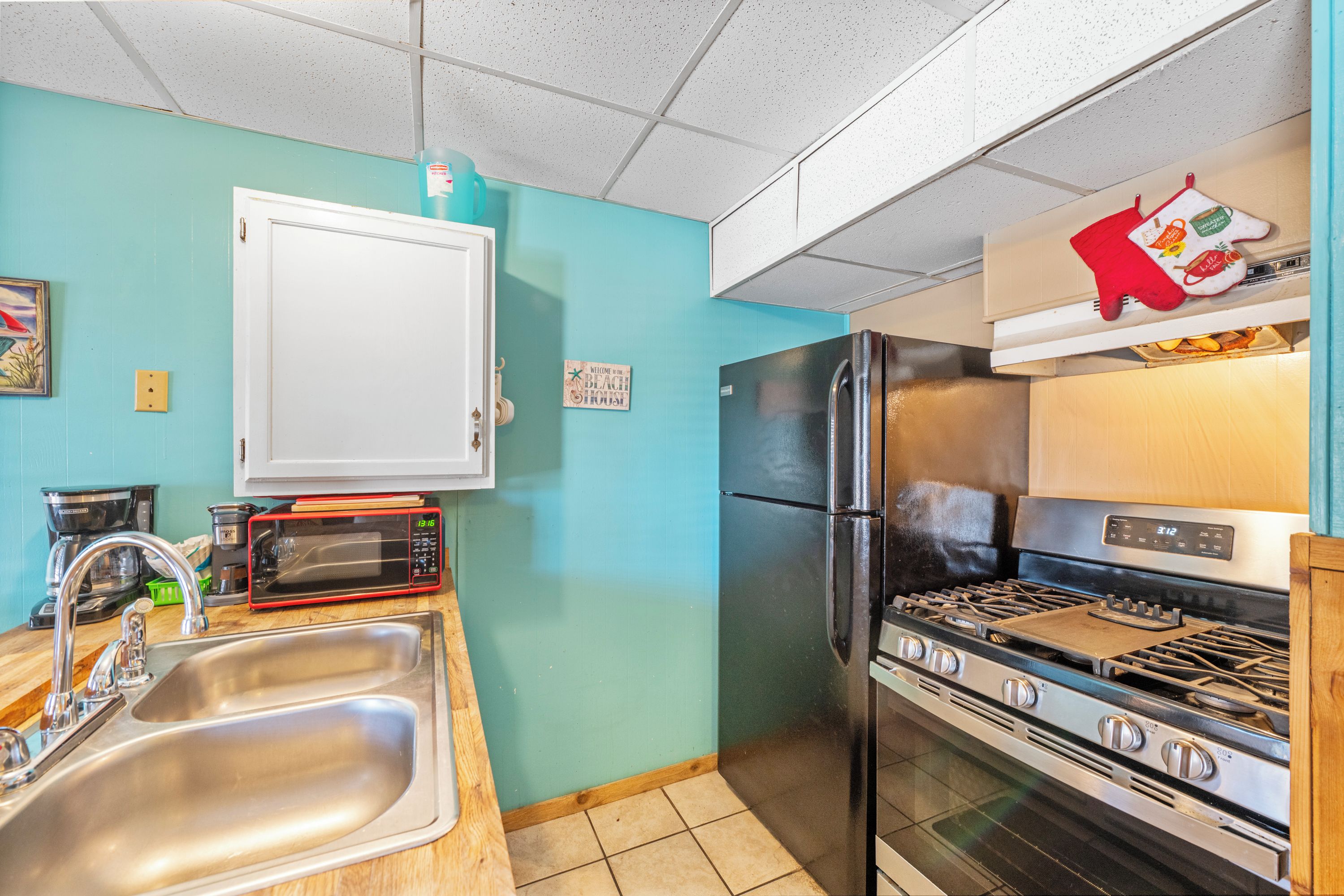 A kitchen with a stainless steel sink, a microwave, a refrigerator, and a stove.