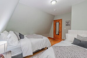 Una camera da letto con due letti, una porta in legno e un cartello fissato al muro.