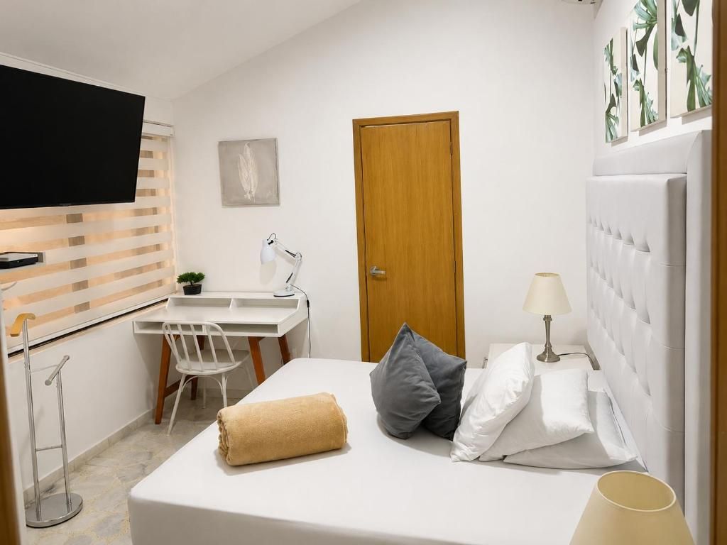 Ett hotellrum med en säng, ett skrivbord, en tv och en dörr.