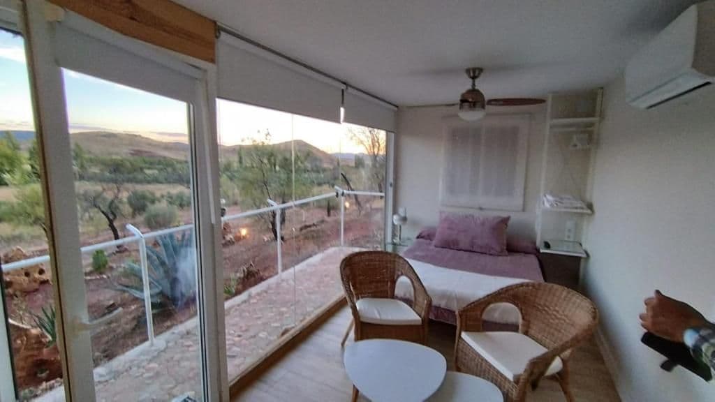 Un balcón con cama, mobiliario de mimbre y vistas al paisaje desértico.