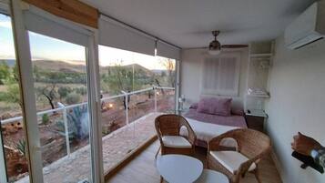 Un balcón con cama, mobiliario de mimbre y vistas al paisaje desértico.