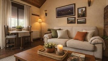 A cozy living room with a sofa, a coffee table, a lamp, and framed pictures on the wall.