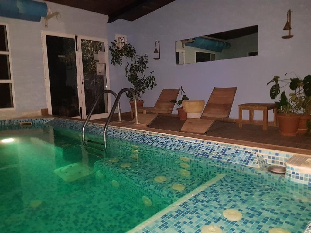 A swimming pool with a tiled edge, a door, and a mirror on the wall.