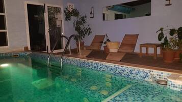 A swimming pool with a tiled edge, a door, and a mirror on the wall.