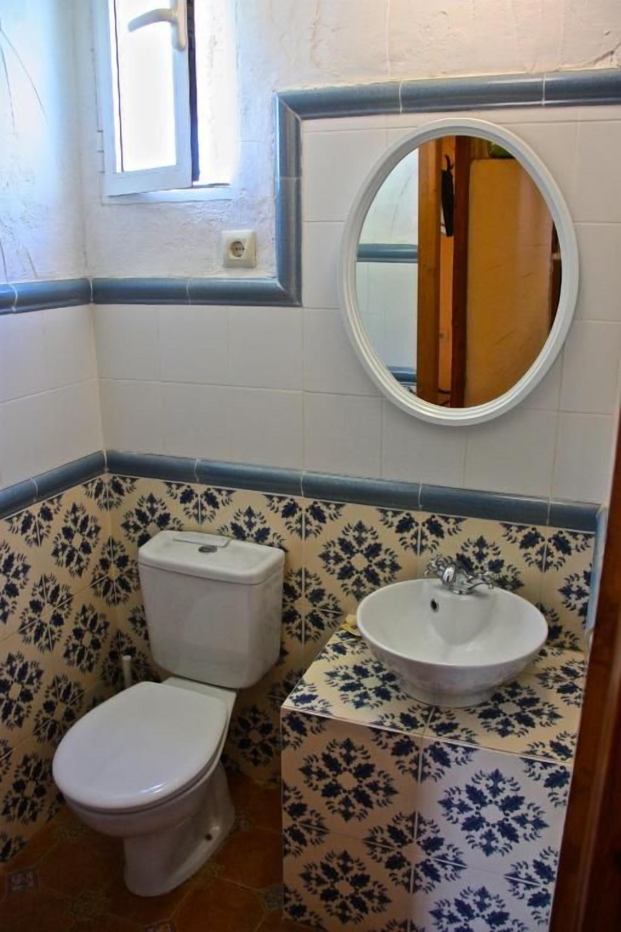 Un baño con inodoro, lavamanos y espejo.