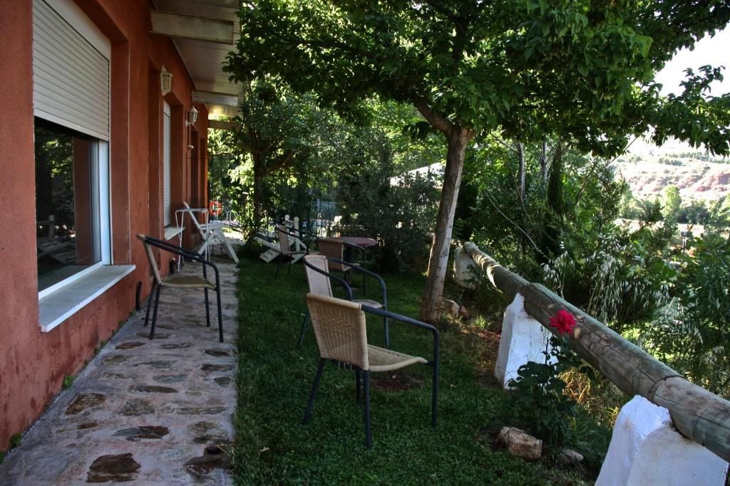 Een terras met stoelen en tafels, een pad van stenen en een uitzicht op een glooiend landschap.