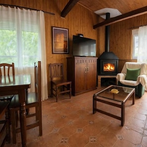 Una habitación acogedora con detalles de madera, chimenea, una mesa de comedor con sillas y un sofá.