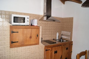 Una cocina con microondas, tostadora, pileta y muebles de madera.