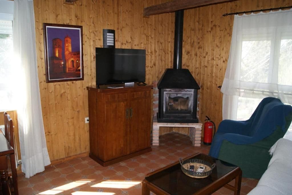 Une pièce aux murs lambrissés, équipée d’une télévision, d’une cheminée, d’un canapé et d’une table.