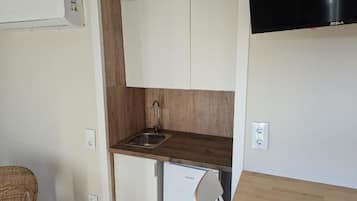 A compact kitchenette with a built-in sink, a small refrigerator, and a microwave.