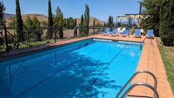 Una piscina rettangolare con una scala in metallo, circondata da una recinzione in metallo nero.