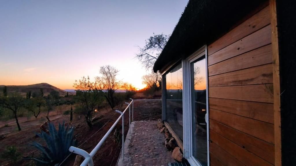Een houten gebouw met een balkon dat uitkijkt over een landschap met bomen en heuvels.