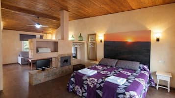 Una camera da letto con un letto, una televisione, un camino e un dipinto raffigurante un tramonto.