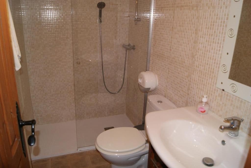 Un baño con ducha, inodoro, lavamanos y espejo.