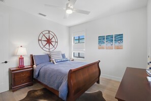 Quarto com cama de madeira, mesa de cabeceira com abajur, decoração de parede com bússola e janela com vista.