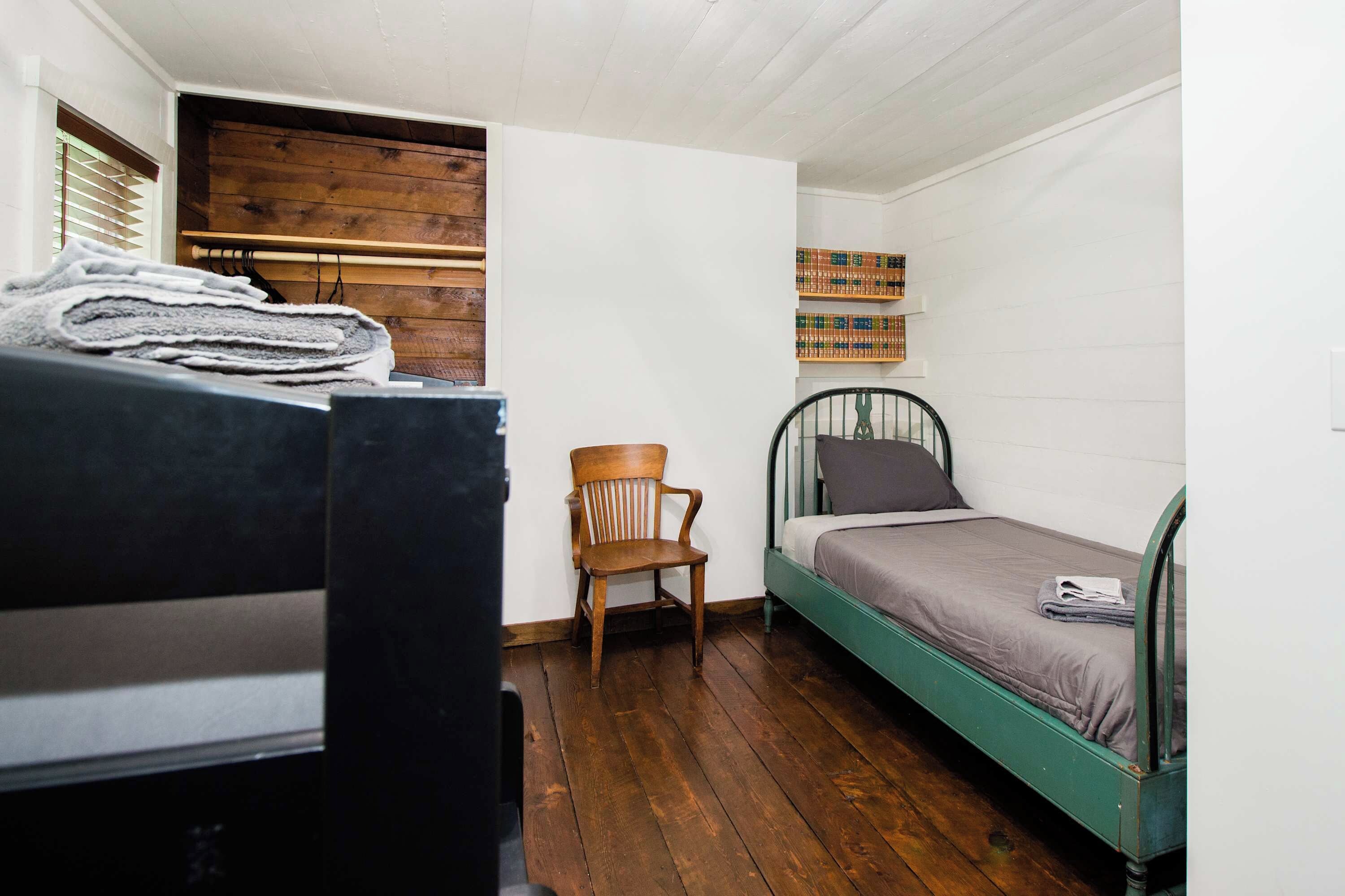 Una stanza piccola e funzionale con un letto a castello, una sedia e una libreria.