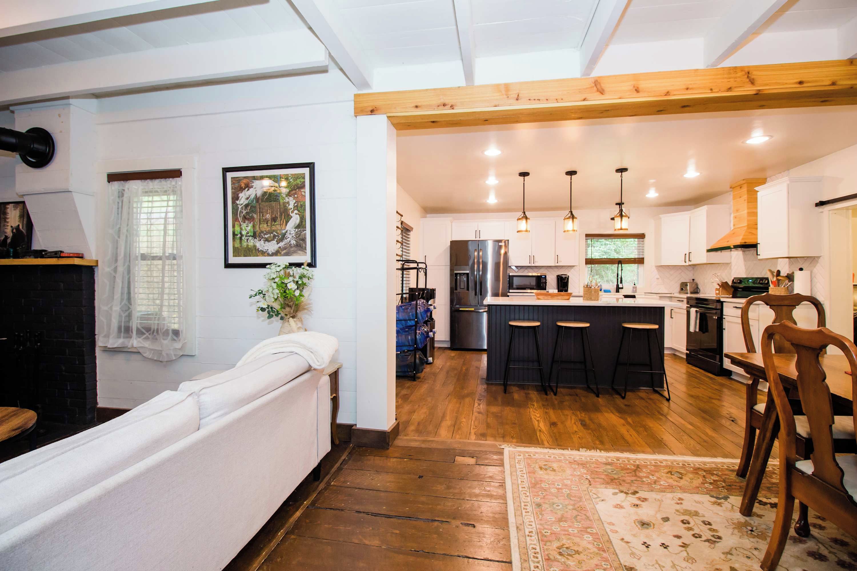 Una cucina moderna con isola centrale, sgabelli da bar e soffitto in legno.