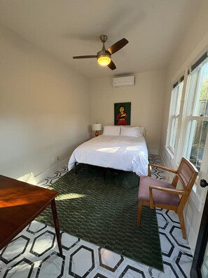 A bedroom with a bed, a chair, a table, a ceiling fan, and a window. - Charming Historic Heights ‘Bungalow Lenú’ (Houston)