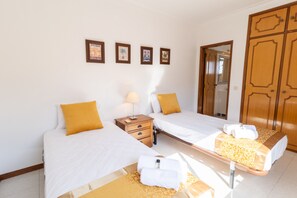 A hotel room with two beds, a nightstand, a lamp, a mirror, and a wardrobe. - VILAMOURA GARDEN VILLA WITH POOL by HOMING (Vilamoura)