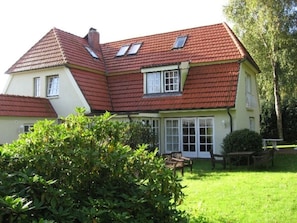 A two-story house with a red-tiled roof, a large glass door entrance, and a well-maintained lawn. - Holiday Home in Wyk on Fohr With Terrace (Wyk auf Foehr)