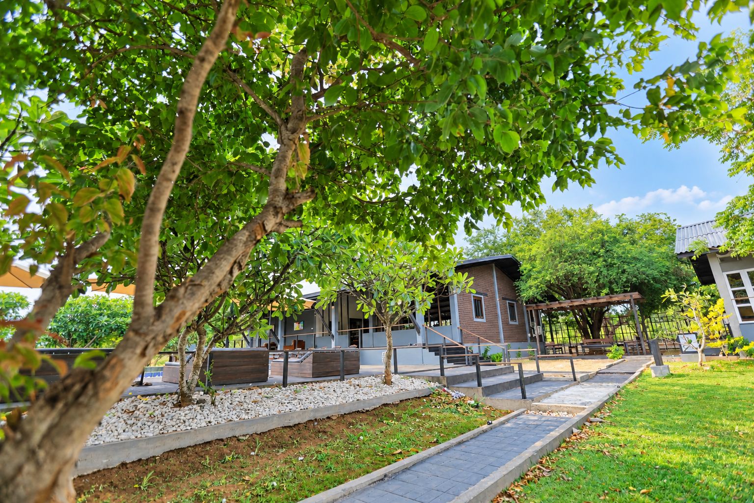 A park with a small building, a wooden pergola, and a pathway.