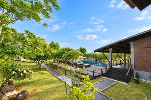 Piscina con muelle de madera, rodeada de árboles y un área de patio techada.