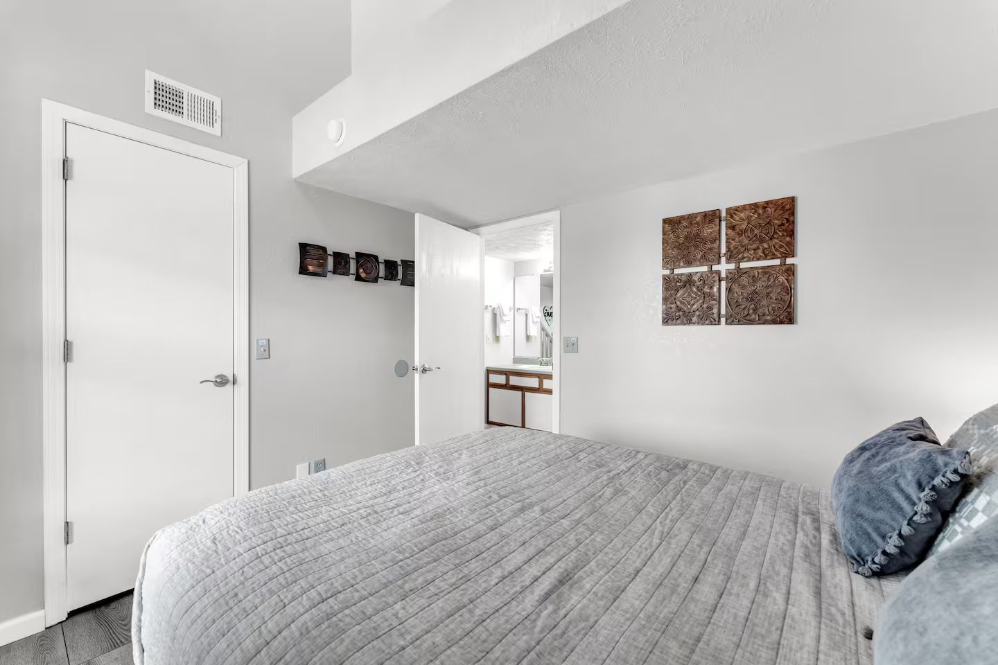 Een slaapkamer met een bed, een deur, een spiegel en decoratieve wandkunst.