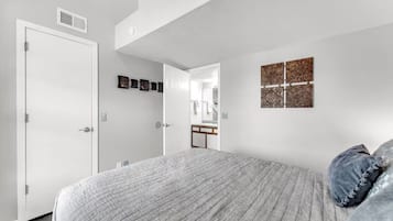 Een slaapkamer met een bed, een deur, een spiegel en decoratieve wandkunst.