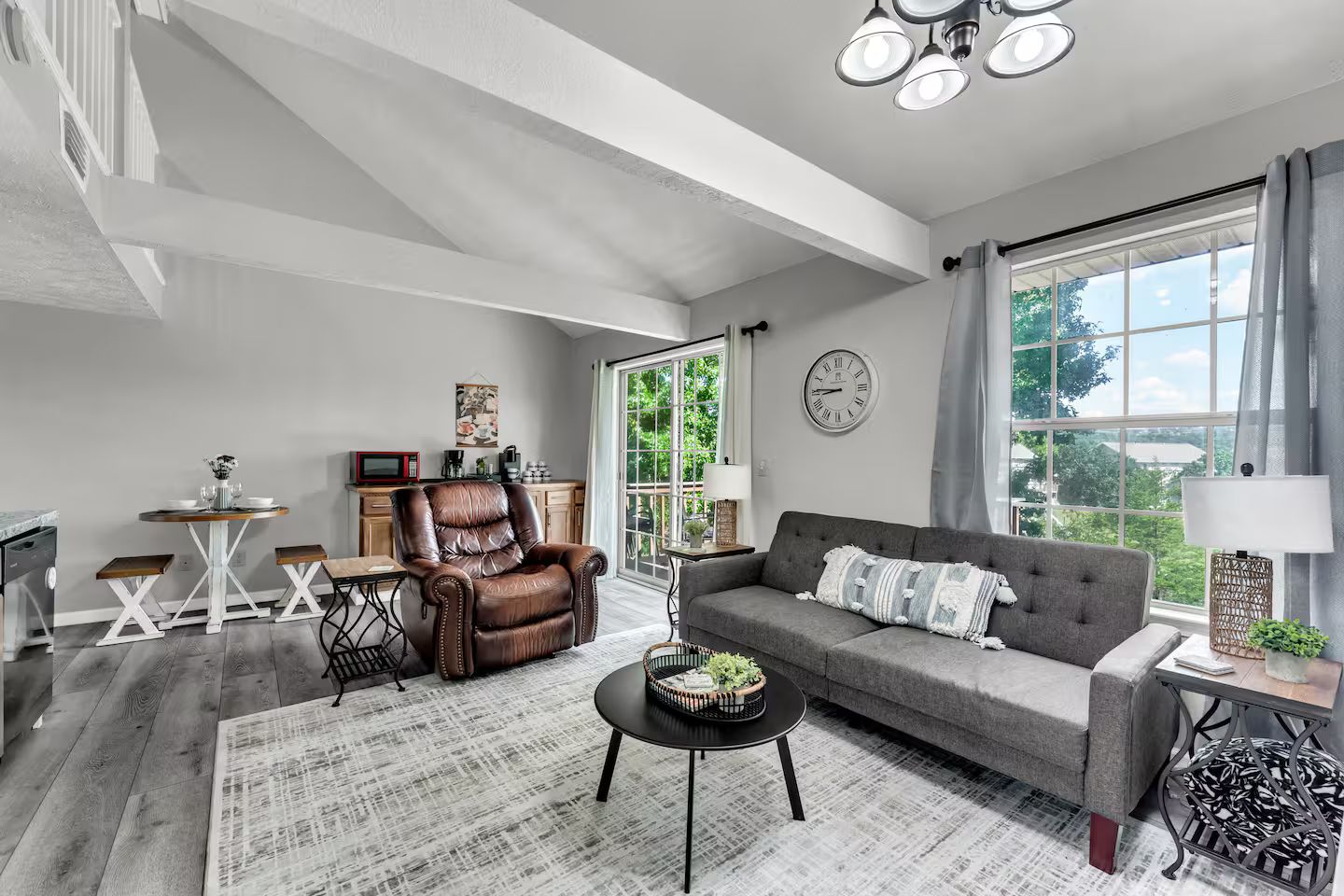 A modern living room with a sofa, armchair, coffee table, and dining area.