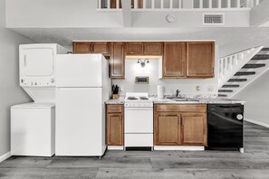 Een moderne keuken met witte apparaten, houten kastjes en een granieten aanrecht.