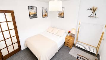 Ein Schlafzimmer mit Bett, Nachttisch, Lampe und einem stehenden Klavier.