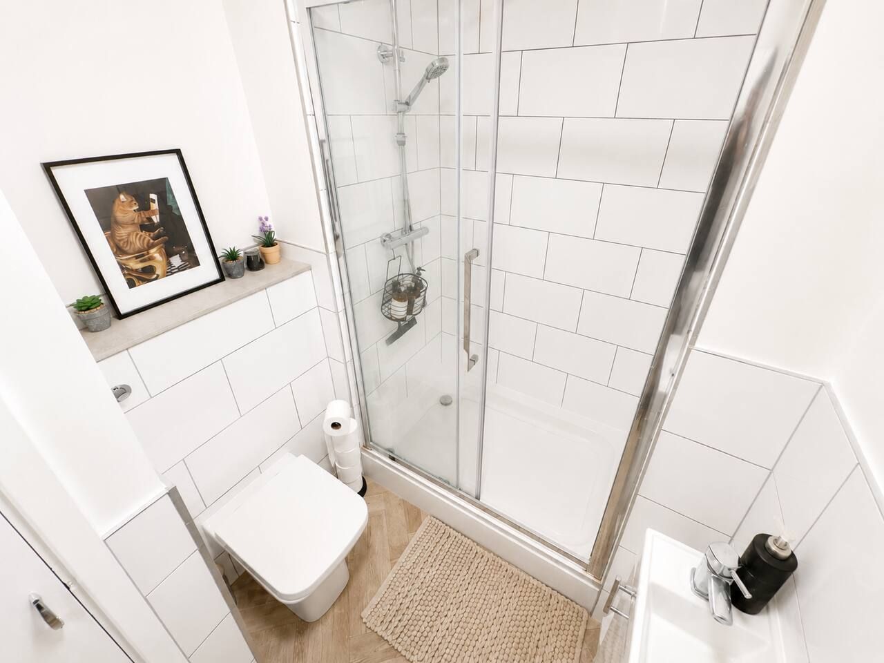 A modern bathroom with a glass shower enclosure, a toilet, and a sink.