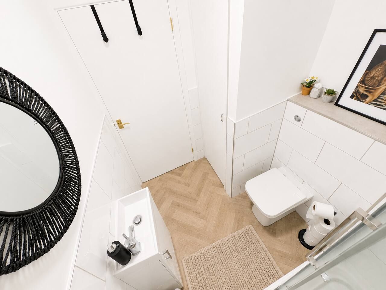 Een kleine badkamer met een wit wastafelmeubel, toilet en spiegel.