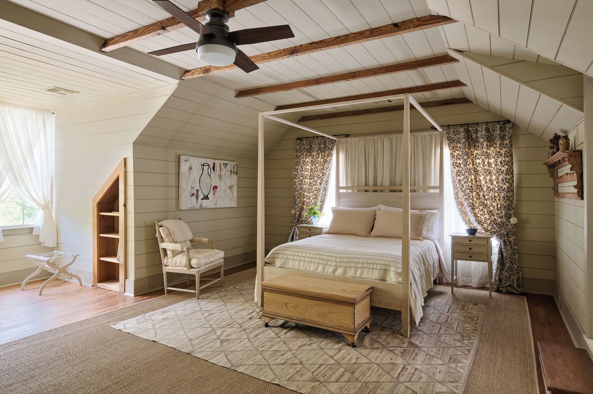 A bedroom with a four-poster bed, a ceiling fan, and a large window with curtains.