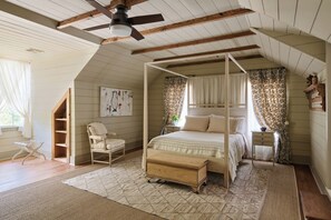 A bedroom with a four-poster bed, a ceiling fan, and a large window with curtains. - Relax & Unwind: Discover the Peaceful Evangeline Suite (Sunset)