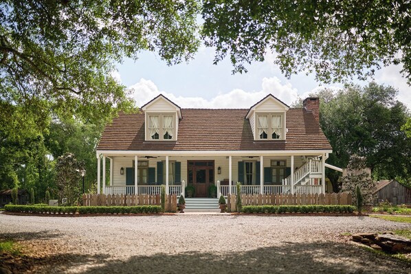 A two-story house with a porch, a front door, and a small front yard. - Relax & Unwind: Discover the Peaceful Evangeline Suite (Sunset)