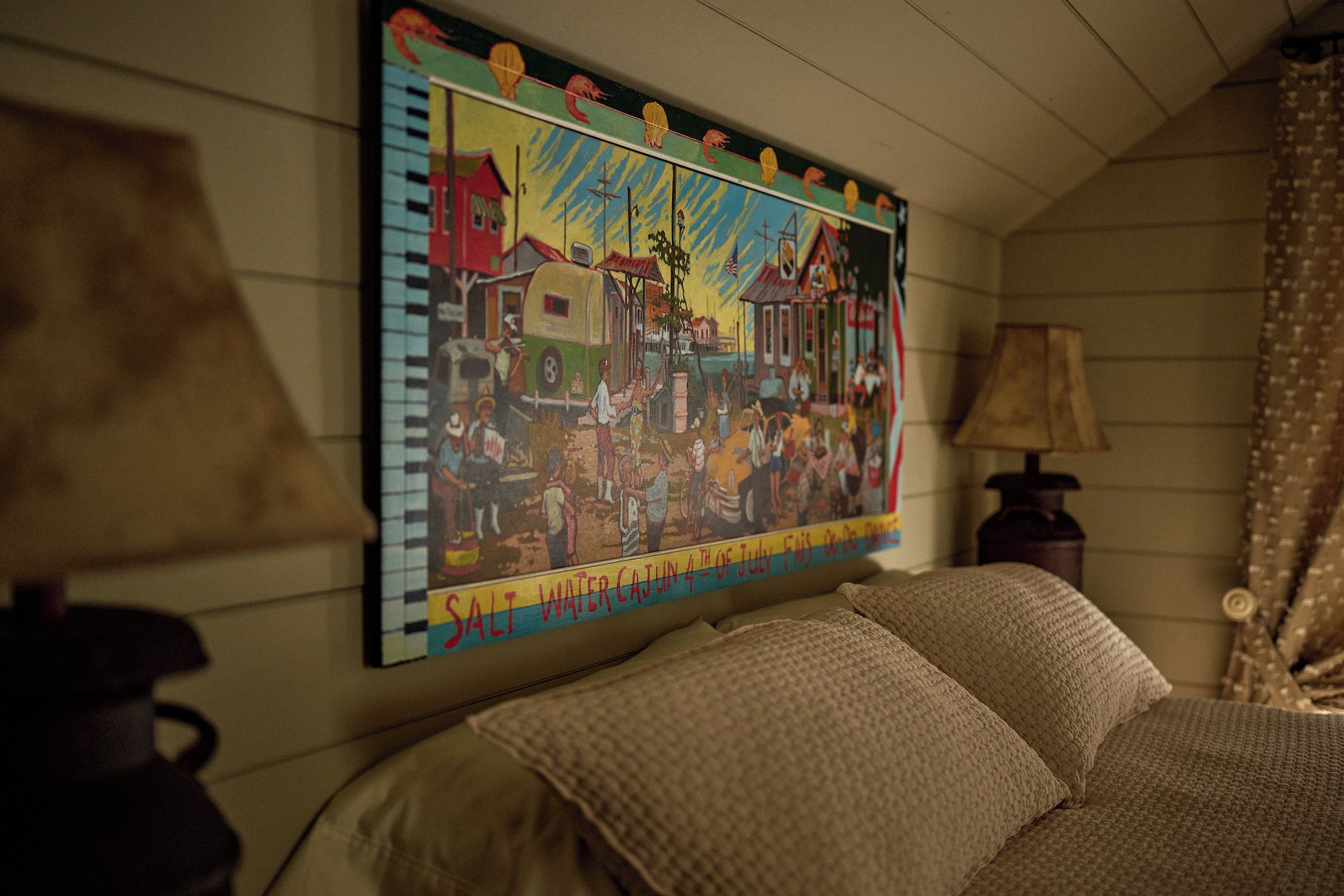 A room with a bed, a wall-mounted painting, a lamp, and a curtain.