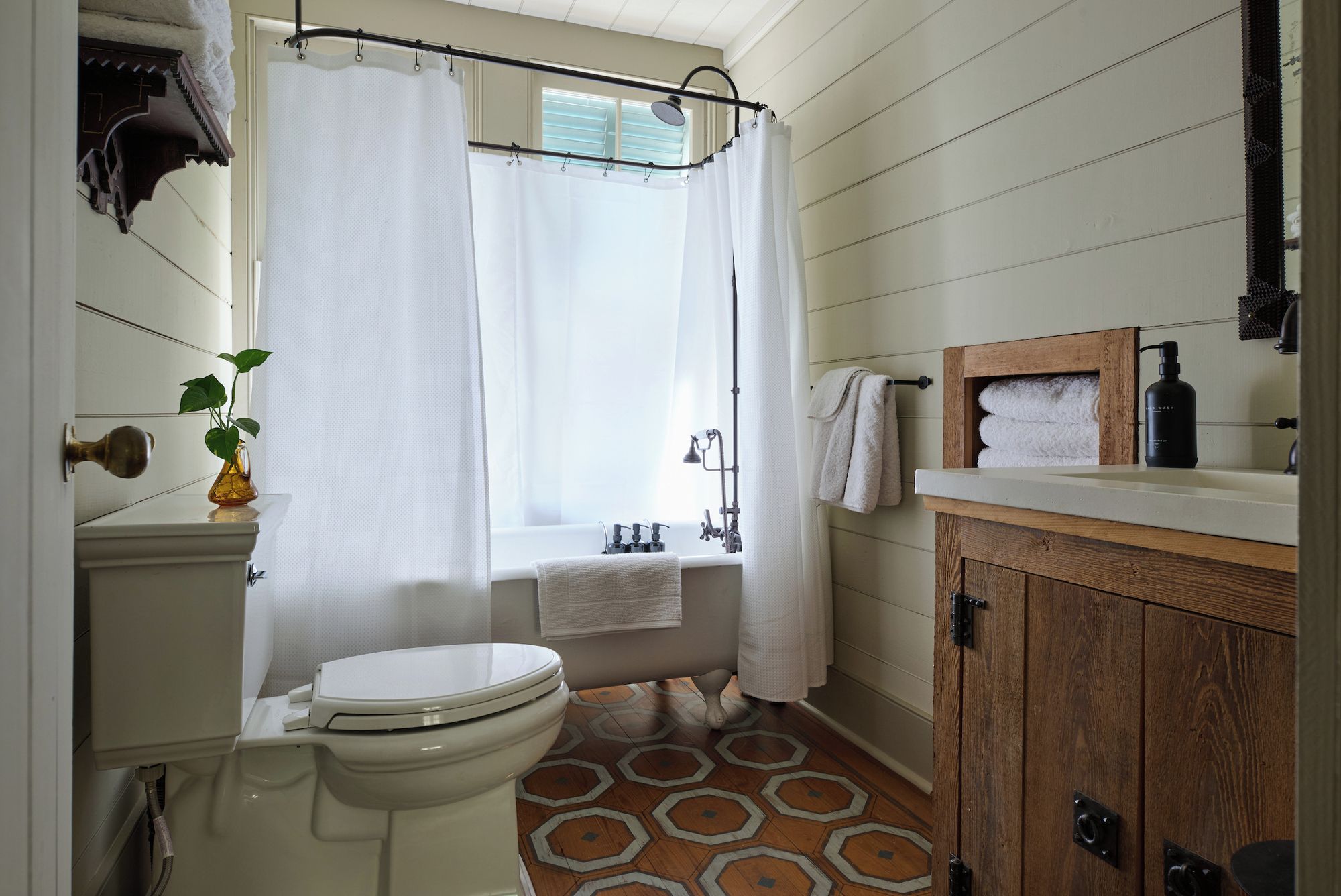 Een badkamer met toilet, douche en een houten kastje.