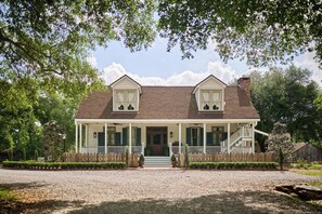 A two-story house with a porch, a front entrance, and a small front yard. - Family-Friendly Comfort in Acadiana: Fais-Do-Do Suite (Sunset)