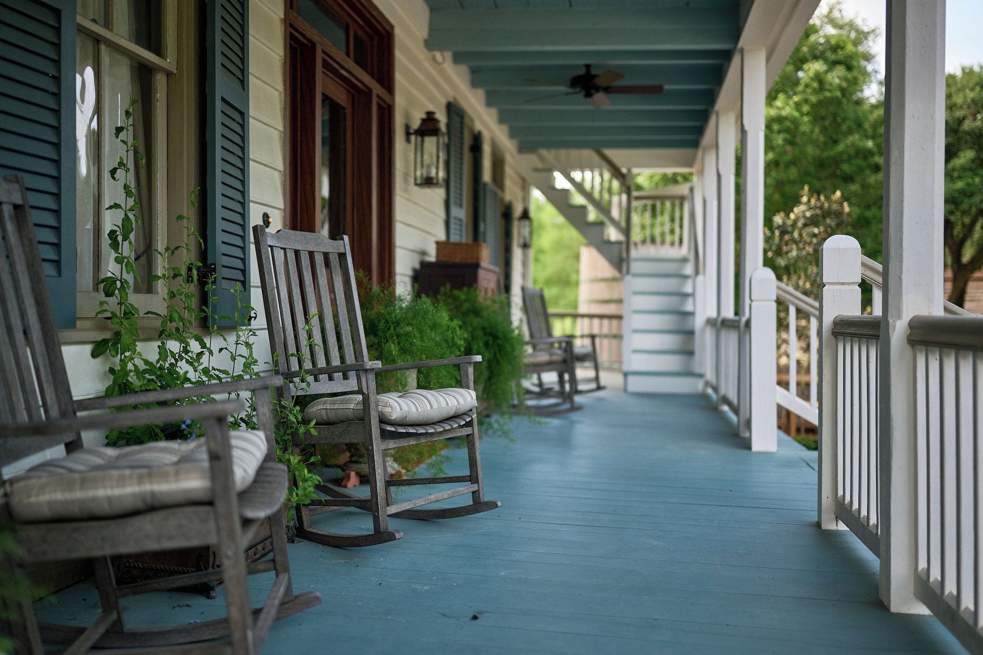 A porch with rocking chairs and a covered walkway.