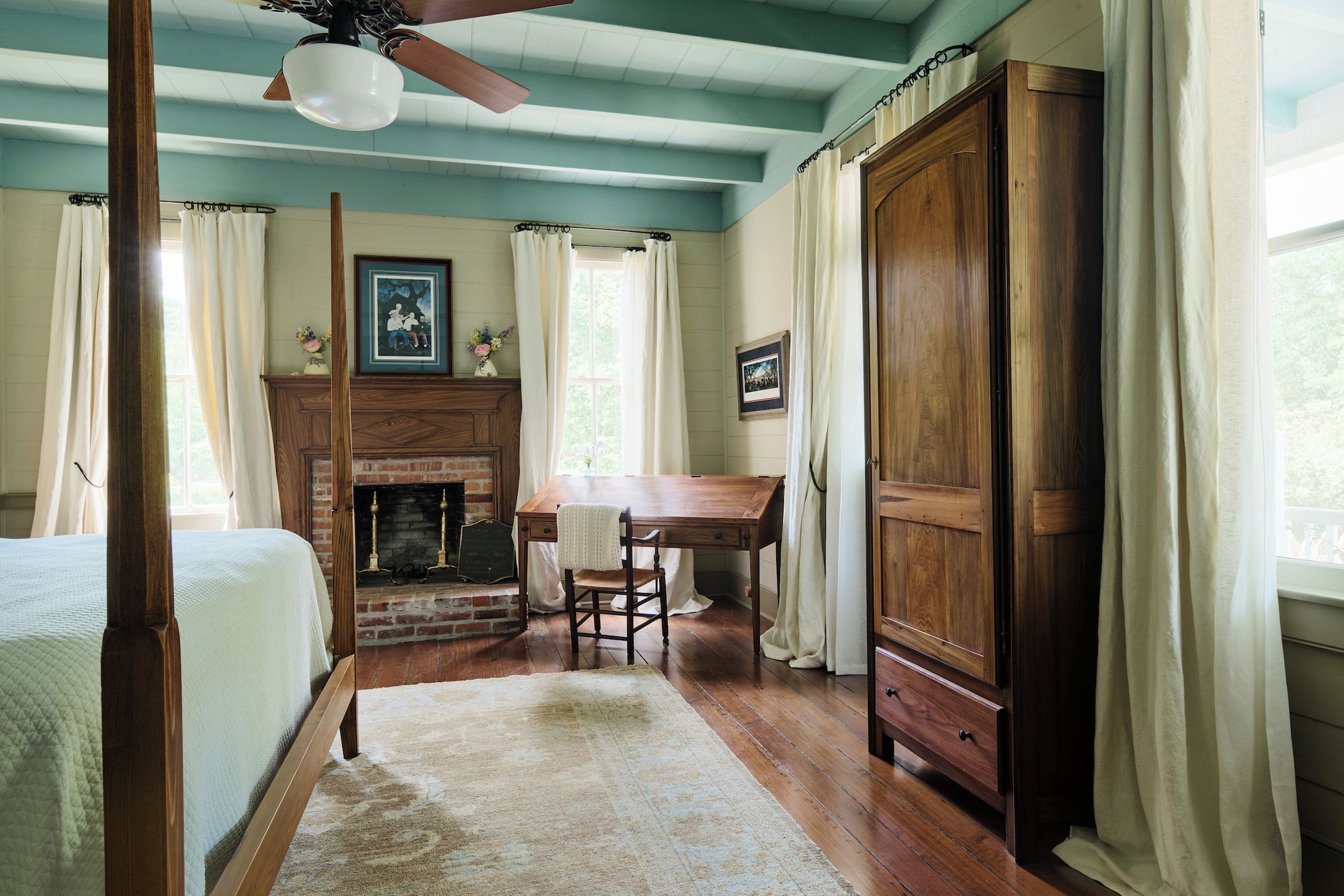A room with a bed, a fireplace, a table with chairs, and a wardrobe.