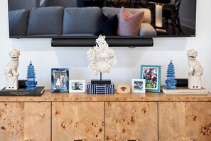 Ein Flachbildfernseher an der Wand über einem Holzschrank mit Dekoration und gerahmten Fotos.