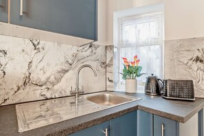 A kitchen with a marble backsplash, a stainless steel sink, and a window with a view. - Host Stay Poplar Apartment (Rochester)