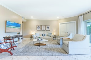 A living room with a sofa, armchairs, a coffee table, and a TV. - Ground-Floor Golf Course Retreat (Miramar Beach)