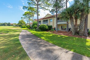 A residential area with a paved walkway, houses with balconies, and a well-maintained lawn. - Ground-Floor Golf Course Retreat (Miramar Beach)