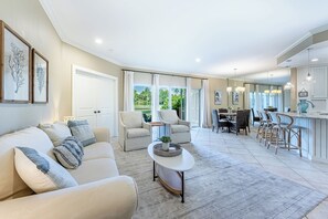 A spacious living area with a sofa, chairs, a coffee table, and a dining area with a table and chairs. - Ground-Floor Golf Course Retreat (Miramar Beach)